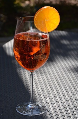 Spritzer ambré dans une coupe à vin avec une tranche d'orange en décoration